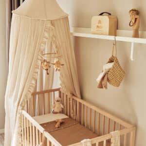 Nougatfärgad sänghimmel med volang från Jollein i ett barnrum med matchande textilier och korgar.